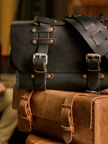No. 4311 Classic Satchel in Black stacked on a Crazy Horse duffle with copper buckles.