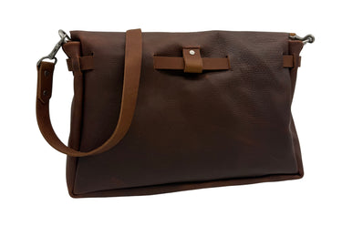 The back side of a dark brown leather shoulder bag with a wide front flap, a coordinating adjustable leather strap, and silver-tone metal hardware, shown on a plain white background.