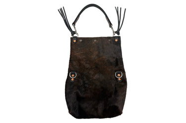 A dark brown hair-on hide shoulder bag with black leather straps, silver-tone hardware, and long black leather fringe tassels, shown against a plain white background.