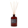 A reed diffuser with amber glass bottle and liquid, multiple light brown reeds inserted, label on front with product information.